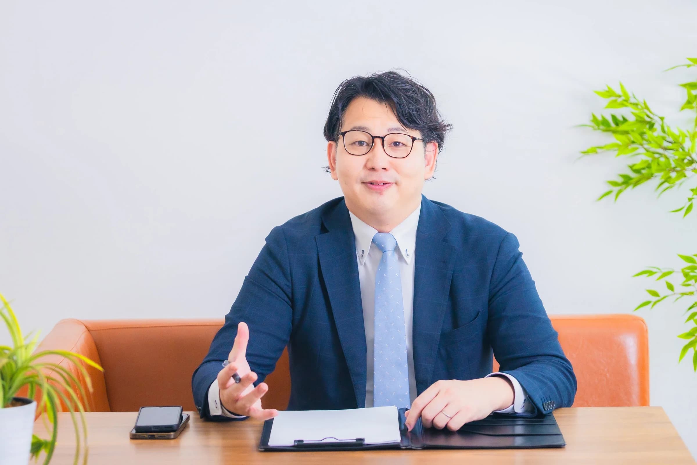 デスクで資料を前に説明する佐藤礼康